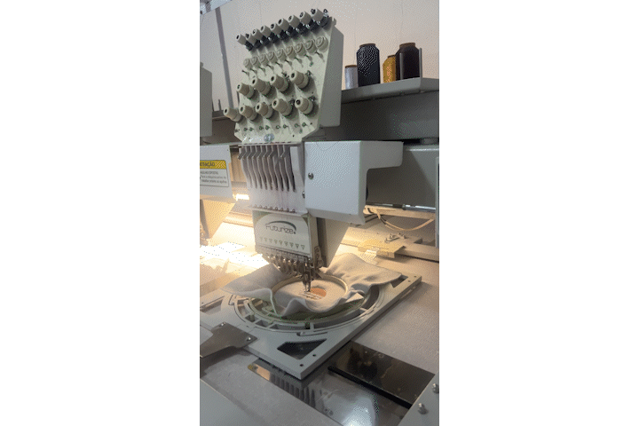 Máquina industrial computadorizada de bordado em funcionamento na fábrica da Ozimme Uniformes